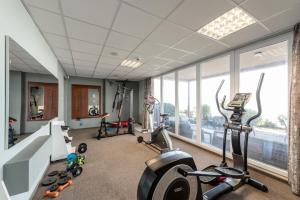 un gimnasio con cintas de correr y elípticas en una habitación con ventanas en Hotel Glamour, en Kaluža