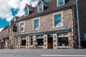 two people riding bikes in front of a brick building at The Sheep and Penguin in Wells