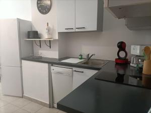 a kitchen with white cabinets and a black counter top at CORSALILA in Calvi