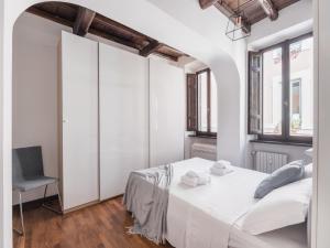 a white bedroom with a bed and a chair at The Best Rent - Elegant apartment in Trastevere in Rome