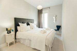 - une chambre blanche avec un grand lit blanc et une chaise dans l'établissement Modern and luxurious -3 Bdr 2Bth- Pastor y Landero, à Séville