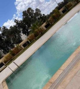 a swimming pool with blue water and trees in the background at Appartement luxueux in Tunis