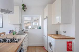 a kitchen with white cabinets and a washer and dryer at Stylish & Homely 1BD Flat - Walthamstow! in London
