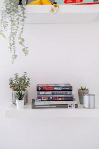 a stack of books on a shelf with potted plants at Stylish & Homely 1BD Flat - Walthamstow! in London
