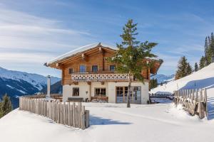 ein Holzhaus im Schnee mit einem Zaun in der Unterkunft Wallegg Lodge - Alpine Premium Chalet - Ski In-Ski Out in Saalbach-Hinterglemm