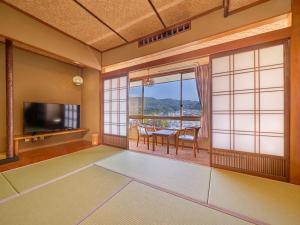 ein Wohnzimmer mit einem TV und einem Tisch mit Stühlen in der Unterkunft Yukai Resort Premium Ureshinokan in Ureshino