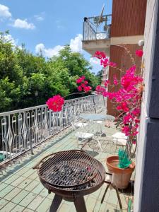 a balcony with a grill and tables and pink flowers at Appartamento con giardino in zona Ponte Milvio e Stadio Olimpico in Rome