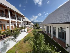 a row of buildings with palm trees in front of them at Madilao Hotel in Luang Prabang