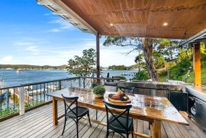 a table and chairs on a deck with a view of the water at The Boathouse in Daleys Point