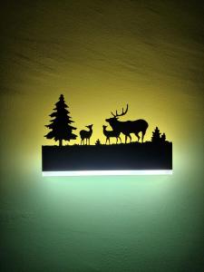 a lighted silhouette of deer and firs on a wall at WH-Bilocale Green Roburent in San Giacomo