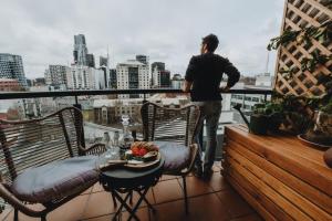 a man standing on a balcony talking on a cell phone at Elegant apartment with balcony and free parking in Melbourne