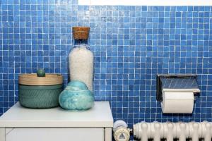 a blue tiled bathroom with a bottle on top of a toilet at Capanna in Wildhaus