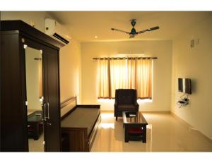 ブバネーシュワルにあるMy Homes and Hotels, Bhubaneswar, Odishaのベッド1台、椅子、窓が備わる客室です。