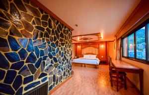 a bedroom with a rock wall with a bed and a desk at Tiger Complex Hotel in Patong Beach