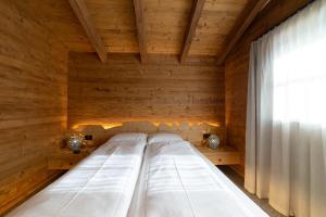 ein großes Bett in einem Holzzimmer mit Fenster in der Unterkunft Chalet Selun in Wildhaus