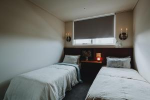 two beds in a room with a large window at Elegant apartment with balcony and free parking in Melbourne