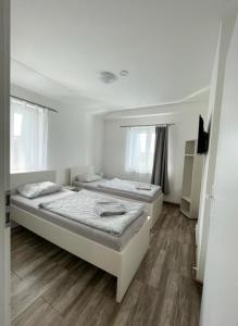 Habitación blanca con 2 camas y suelo de madera. en Apartmány Plzeň Zábělá 69, en Plzeň