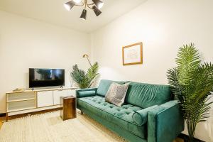uma sala de estar com um sofá verde e uma televisão em Apartment 189: Upper East Side em Nova York
