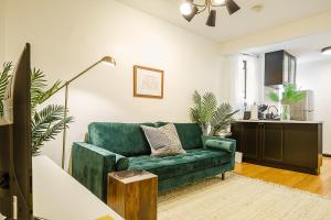 uma sala de estar com um sofá verde e uma cozinha em Apartment 189: Upper East Side em Nova York