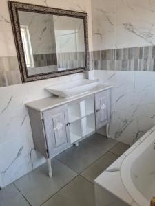 uma casa de banho com um lavatório, um espelho e uma banheira em @336 Bourke em Pretoria