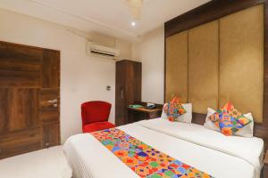 MuthiganjにあるFabHotel Stay Inn Iのベッドと赤い椅子が備わるホテルルームです。