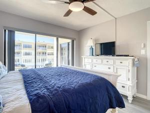 een slaapkamer met een bed met een blauw dekbed en een televisie bij Coastal Living at its Best Ocean View Castle Reef 409 in New Smyrna Beach