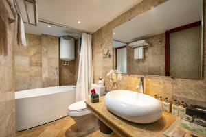 a bathroom with a sink and a tub and a toilet at Oriental Suites Hotel & Spa in Hanoi