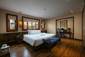a bedroom with a large white bed and a desk at Oriental Suites Hotel & Spa in Hanoi