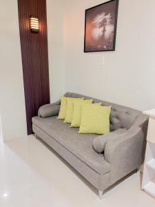 uma sala de estar com um sofá cinzento com almofadas amarelas em 2 Bedroom and 1 Bedroom Apartments with Private Pool and Gym em Puerto Princesa