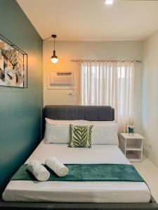 a bedroom with a large bed with two pillows at 2 Bedroom and 1 Bedroom Apartments with Private Pool and Gym in Puerto Princesa City