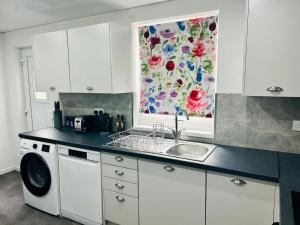 a kitchen with a sink and a washing machine at Elmbank Avenue House by Klass Living Uddingston in Uddingston