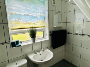 Elmbank Avenue House by Klass Living Uddingston في أودينغستن: حمام مع مغسلة ونافذة بها لوحة