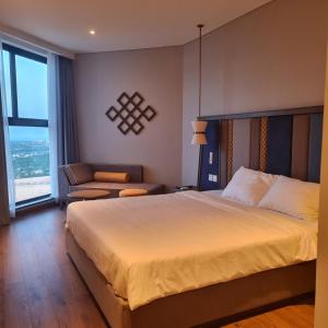 una habitación de hotel con una cama grande y una silla en Apec mandala mũi né, en Phan Thiet