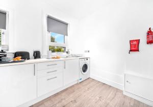 a white kitchen with a washing machine and a window at Sanderson Apartment by Klass Living Uddingston in Uddingston