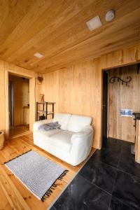 ein weißes Sofa in einem Zimmer mit Holzwänden in der Unterkunft Pirtsmāja diviem Līčezeri in Balvi