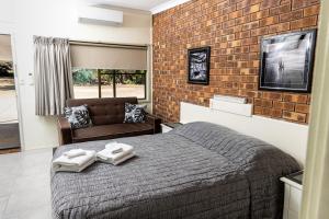 a bedroom with a bed and a brick wall at Benaraby Hilltop MotorInn in Benaraby