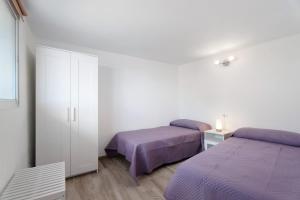 2 camas en una habitación blanca con sábanas moradas en Vivienda vacacional La Era en Vallehermoso