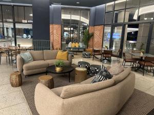 a lobby with couches and tables in a building at Cosy Waterfall Midrand Apartment in Midrand