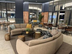 a lobby with couches and tables in a building at Cosy Munyaka Waterfall Apartment in Midrand