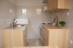 a small kitchen with wooden cabinets and a sink at House Baglija in Lumbarda