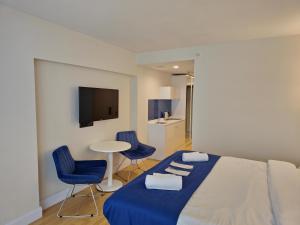 1 Schlafzimmer mit einem Bett, 2 blauen Stühlen und einem Tisch in der Unterkunft ORBI Sea Breeze ApartHotel in Batumi