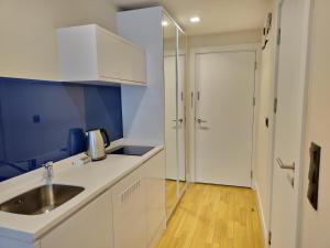a kitchen with white cabinets and a sink and a door at ORBI Sea Breeze ApartHotel in Batumi