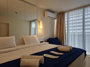 una camera d'albergo con un grande letto con due asciugamani di ORBI Sea Breeze ApartHotel a Batumi