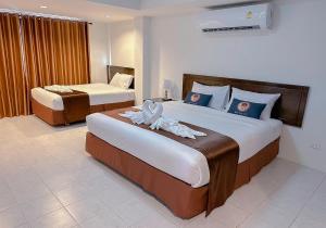 a hotel room with two beds with towels on them at RoomQuest Kalim Beach in Patong Beach