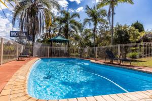 a swimming pool with two chairs and a gazebo at Benaraby Hilltop MotorInn in Benaraby