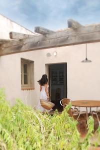 Uma mulher de vestido branco à porta de uma casa. em Ca la Merce Batista em Palau-Saverdera