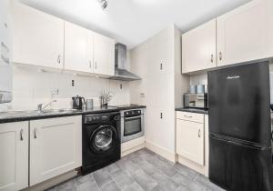 cocina con armarios blancos y lavavajillas negro en Garturk Apartment by Klass Living Coatbridge en Coatbridge
