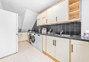 cocina con armarios blancos, lavadora y secadora en Rothesay House by Klass Living Coatbridge, en Coatbridge