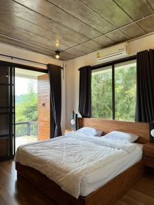 - une chambre avec un grand lit et une grande fenêtre dans l'établissement 11 House Mae rim by Kohei, à Mae Rim