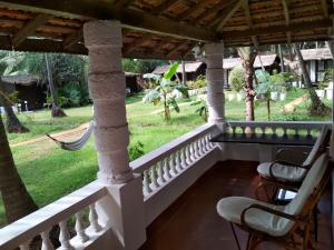 a porch with two chairs and a hammock at Mamagoa Beach Resort in Mandrem
